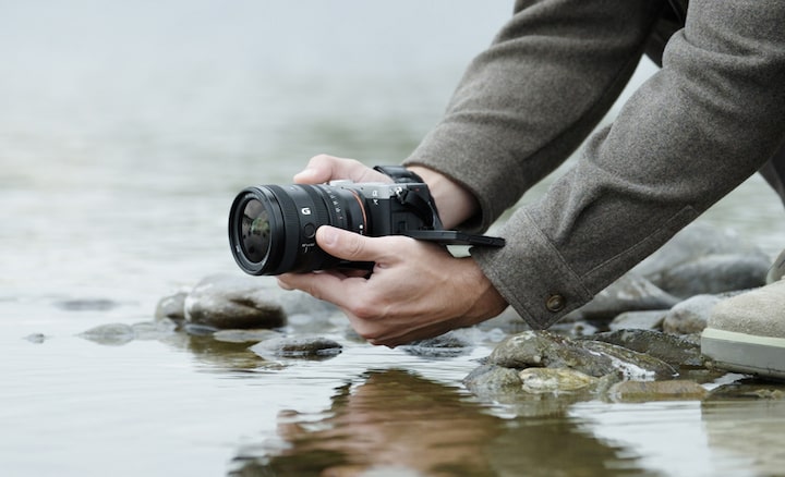 Imagen que muestra a un usuario con la α7CII con el lente FE 24-50 mm F2.8 G cerca de un río. El usuario está capturando imágenes desde abajo